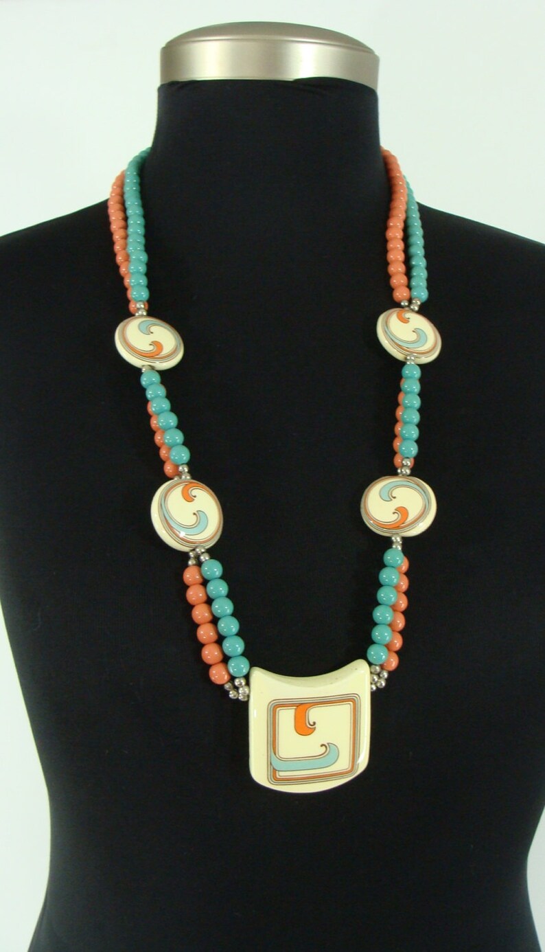 May include: A double strand necklace with coral and turquoise beads and a large pendant with a swirl design.