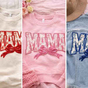 May include: Three items of apparel are displayed: a cream-colored sweatshirt, a pink sweatshirt, and a denim jacket. Each item features the word "MAMA" in a floral design with a bow. The cream sweatshirt has red accents, the pink has pink, and the denim jacket has blue.