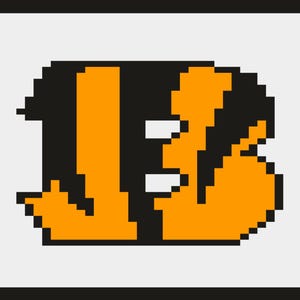 Peut inclure: Nombre 13 pixelisé en orange et noir sur fond gris clair. Le chiffre est de style rétro et en blocs, avec des bordures noires en haut et en bas. Le design rappelle un logo d'équipe sportive.