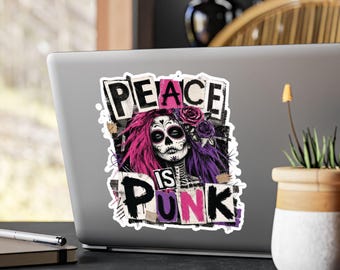 May include: A rectangular sticker on a laptop featuring a sugar skull character with vibrant pink and purple hair, adorned with roses. The text PEACE IS PUNK is displayed in bold, distressed black and pink lettering against a dark, textured background.