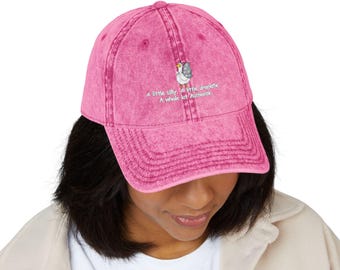 May include: Pink baseball cap with a distressed finish. The cap features an embroidered design of a goose and the text "A little silly, A little dramatic, A whole lot Authentic."
