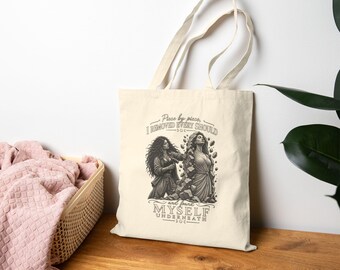 May include: A cream-colored canvas tote bag featuring a black and white graphic illustration of a person chiseling away stone from a figure, with the text: Piece by piece, I REMOVED EVERY SHOULD and found MYSELF UNDERNEATH, accented by moon icons.