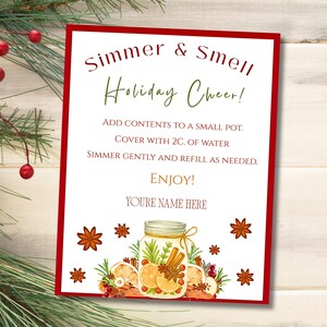 Op de afbeelding: Een feestelijk bord met een rode rand en de tekst "Simmer & Smell Holiday Cheer!". Het bord bevat instructies en een illustratie van een pot met kaneelstokjes, sinaasappelschijfjes en steranijs. Decoratieve takjes en bessen omringen het bord.