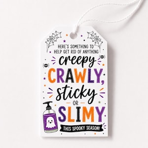Può includere: Un'etichetta regalo rettangolare bianca con cordino, con testo nero, arancione e viola che recita: HERE'S SOMETHING TO HELP GET RID OF ANYTHING creepy CRAWLY, sticky OR SLIMY THIS SPOOKY SEASON! Include grafiche di ragnatele e un fantasma.