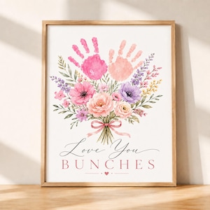 May include: A framed print featuring a watercolour bouquet of pink, purple, and yellow flowers with two handprints in shades of pink at the top. A pink ribbon ties the stems together. The text reads Love You BUNCHES with a small heart below.
