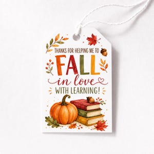 Może przedstawiać: Biała, prostokątna zawieszka prezentowa z białym sznurkiem, ozdobiona akwarelową ilustracją dyni, stosu trzech książek, żołędzia i jesiennych liści. Tekst na zawieszce brzmi: THANKS FOR HELPING ME TO FALL in love WITH LEARNING!