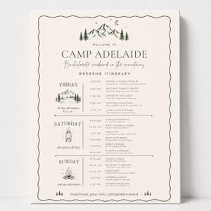 May include: A cream-coloured weekend itinerary sign for Camp Adelaide featuring black text and mountain illustrations. The schedule outlines Friday, Saturday, and Sunday activities including arrival, hiking, and brunch, framed by a wavy border.