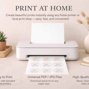 May include: A white printer is shown printing circular labels with a heart design. The image includes a coffee mug, a succulent, a vase with dried flowers, and books. Text reads "Print at Home" and describes the ease of printing.