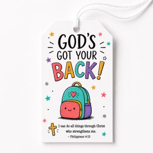 May include: A white rectangular gift tag with a string, featuring the black text GOD'S GOT YOUR BACK! above a colorful cartoon backpack illustration. Below is the text I can do all things through Christ who strengthens me. - Philippians 4:13.