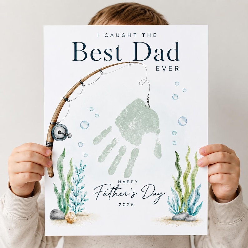 May include: A Father's Day print featuring a handprint design with a fishing rod illustration. The text reads "I Caught the Best Dad Ever" and "Happy Father's Day 2026". The print includes watercolor elements of seaweed and bubbles.
