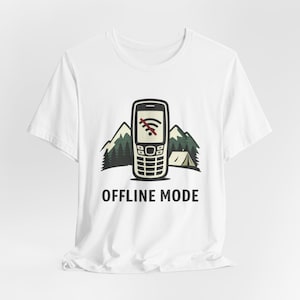 Op de afbeelding: Wit T-shirt met een afbeelding van een retro mobiele telefoon met een doorgestreept Wi-Fi-symbool, tegen een achtergrond van bergen en een tent. De woorden "OFFLINE MODE" staan eronder.