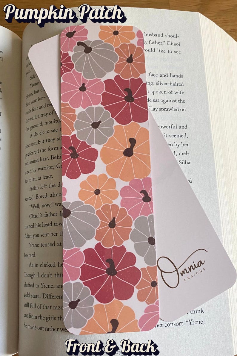 Puede incluir: Marcap&aacute;ginas decorativo con un dise&ntilde;o de calabazas en tonos rosa, naranja y gris. El marcap&aacute;ginas est&aacute; insertado en un libro. Los textos "Pumpkin Patch" y "Front & Back" son visibles.