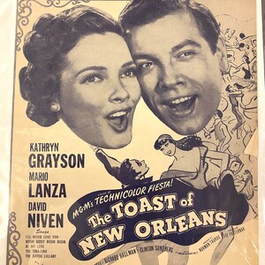May include: A vintage movie poster for the musical film "The Toast of New Orleans" starring Kathryn Grayson and Mario Lanza. The poster features a black and white image of the two actors singing together. The poster also includes the title of the film, the names of the actors, and the song "Be My Love".