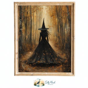 May include: A framed wall art print depicting a figure in a long black dress and a pointed hat walking away through a golden autumn forest. The scene features tall trees, fallen leaves on the ground, and a soft light. Below the frame is a small logo.
