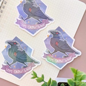 May include: Three stickers featuring a stylized crow with red eyes and a futuristic design. The crow is set against a diamond-shaped background with a purple and blue gradient. The text "Hot Crow Walk" is on a banner.