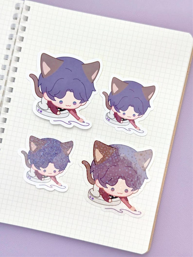 May include: Four stickers featuring a cartoon character with cat ears and purple hair. The character is wearing a maroon outfit and is posed as if drawing. The stickers are on a white grid paper notebook.