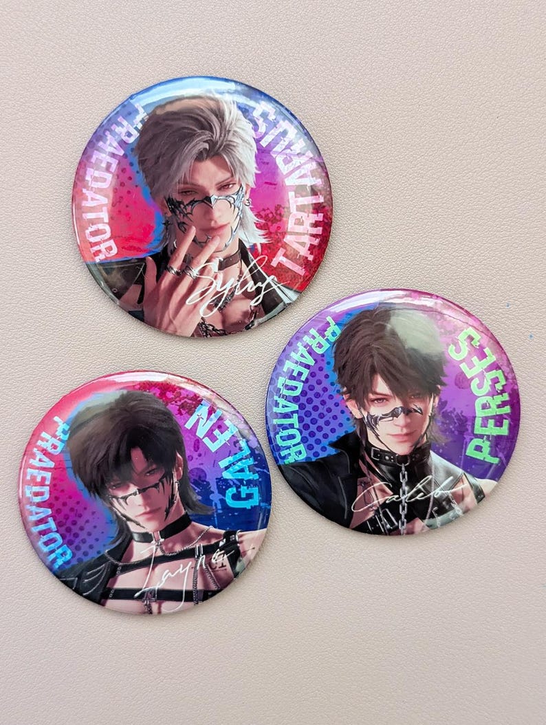 May include: Three round pinback buttons with anime-style character illustrations. Each button features a different character with detailed facial features, wearing dark clothing and accessories. The buttons have a colorful background with text around the edges.