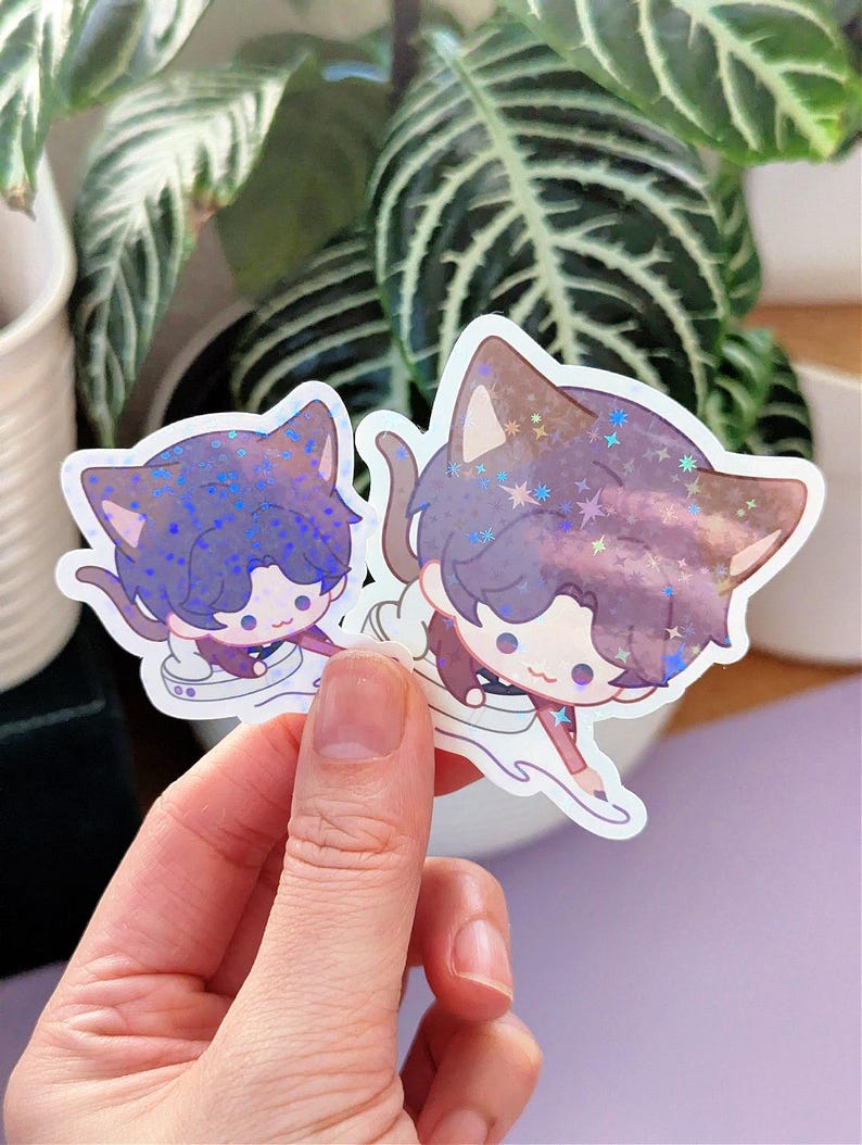 May include: Two cat-shaped stickers with anime-style illustrations. The stickers feature a purple and brown color scheme with glitter accents. The cat characters have cute expressions and are depicted in a dynamic pose, with a white outline.