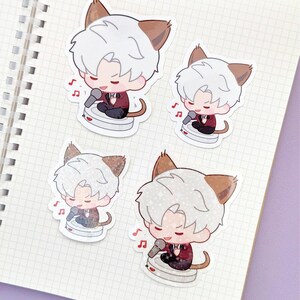 May include: Four stickers featuring a cartoon character with white hair, cat ears, and a red jacket, singing into a microphone. Each sticker has a musical note icon. The stickers are on a notebook page.