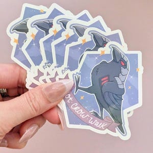 May include: A stack of stickers featuring a stylized black crow-like character with red accents, set against a purple and blue starry background. The stickers have a banner that reads "rot crow walk".