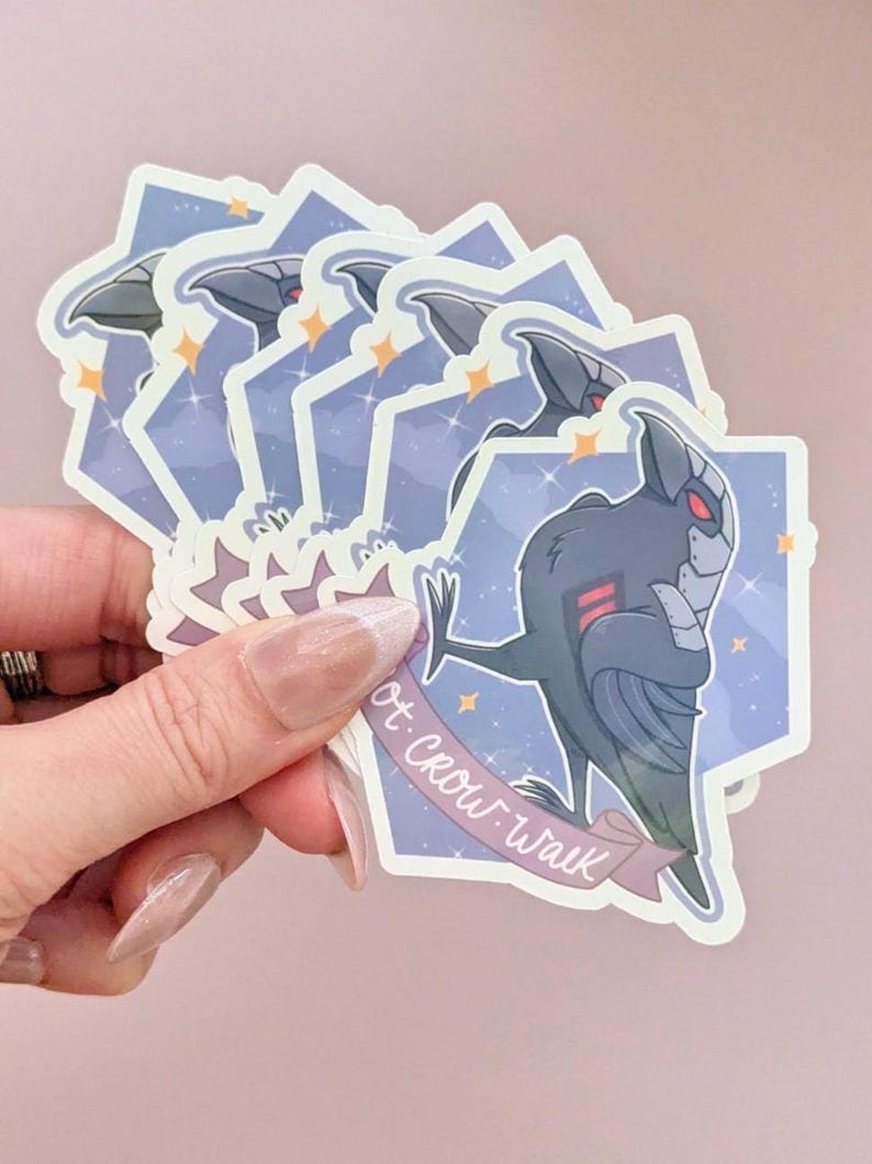 May include: A stack of stickers featuring a stylized black crow-like character with red accents, set against a purple and blue starry background. The stickers have a banner that reads "rot crow walk".