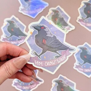 May include: A collection of stickers featuring a stylized crow with red eyes and metallic accents. The crow is set against a purple and blue diamond-shaped background with the text "Hot Crow Walk" on a banner.