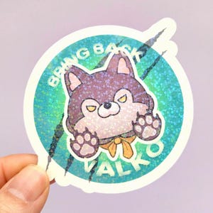 May include: A circular holographic sticker featuring a cartoon purple wolf character with yellow eyes and a yellow neck ribbon. The background is a teal gradient with black claw marks and the white text BRING BACK VALKO arched around the wolf.