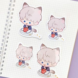 May include: Four stickers featuring a cartoon character with cat ears, light gray hair, and blue eyes. The character is wearing a dark blue suit and holding a red container. The stickers are on a white notebook page with a grid pattern.
