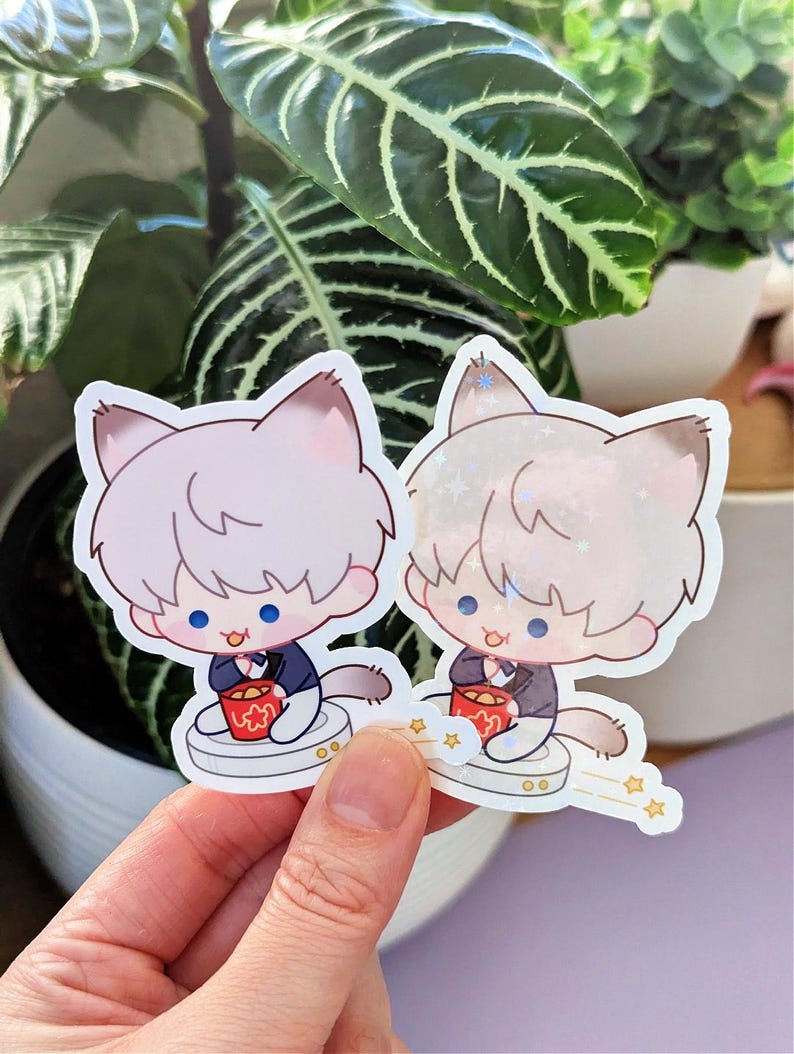 May include: Two cat-themed stickers. Each sticker features a cartoon cat character with light-colored fur, wearing a dark blue suit and holding a red cup. The stickers have a white border and are set against a background of green plants.