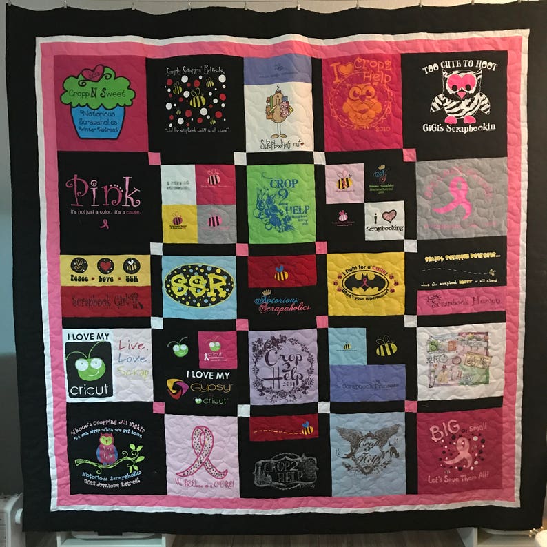 May include: A pink and black quilt with various squares featuring different designs and text. Some of the squares feature text like "Crop 2 Help", "I Love My Cricut", "Too Cute to Hoot", and "Pink".
