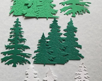 May include: Assortment of green and white paper die-cut pine tree shapes. The trees are various sizes and have a textured surface.