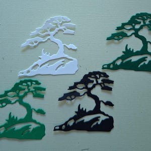 May include: Five bonsai tree cutouts in white, green, and black. The trees are on a light green background. The trees are stylized with detailed branches and sit on a rocky base.