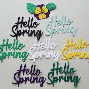 May include: Assortment of seven "Hello Spring" die cuts in various colors, including black, green, white, yellow, and purple. The die cuts are arranged in a semi-circle with a purple flower die cut at the top.