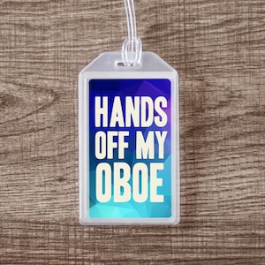 May include: A blue and white luggage tag with the text "Hands Off My Oboe" printed on it.