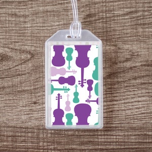 May include: A clear plastic luggage tag with a white background and a repeating pattern of purple and green violin silhouettes.