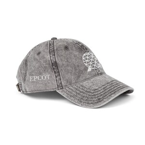 Può includere: Cappellino da baseball grigio con la scritta "EPCOT" ricamata in bianco sul lato. Il cappellino presenta un design geometrico bianco sul davanti e un cinturino regolabile. Il cappello è realizzato in tessuto invecchiato.