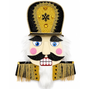 May include: A decorative nutcracker wall hanging featuring a black and gold glittered hat with a central snowflake emblem. The face has blue eyes, pink cheeks, a black mustache, and white faux fur hair and beard, with gold fringe epaulets.