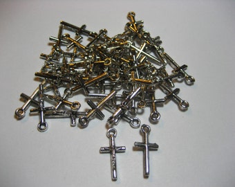 May include: A large pile of silver-toned metal cross charms. The charms are small and delicate, with a simple design. They are perfect for adding a touch of faith to jewelry or crafts.