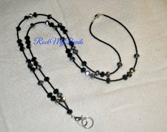 May include: A black and silver beaded lanyard with a silver clasp. The lanyard is made of small, round beads and is approximately 30 inches long.