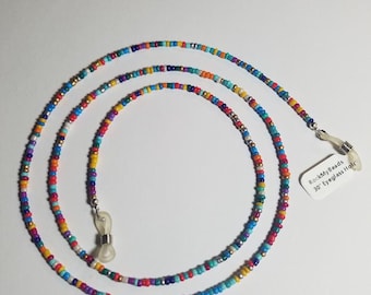 May include: A colorful beaded eyeglass chain with silver clasps. The chain is made of small, multi-colored beads and is approximately 30 inches long. The chain is coiled and laid out on a white surface. A small white tag with the text "RockMyBeads 30" Eyeglass Holder" is attached to the chain.