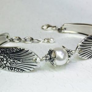 May include: A silver bracelet made from a vintage spoon with a pearl and floral design.