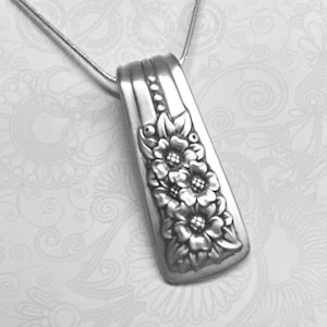 May include: A silver necklace with a pendant featuring a floral design. The pendant is made from a repurposed silverware piece.