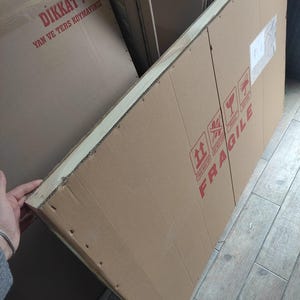 K&ouml;nnte beinhalten: Gro&szlig;er rechteckiger Karton mit rotem FRAGILE-Aufdruck. Der Karton ist mit Klebeband versiegelt und tr&auml;gt Versandetiketten. Der braune Karton scheint neu zu sein.