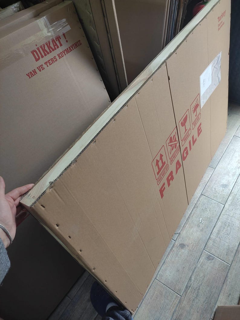 K&ouml;nnte beinhalten: Gro&szlig;er rechteckiger Karton mit rotem FRAGILE-Aufdruck. Der Karton ist mit Klebeband versiegelt und tr&auml;gt Versandetiketten. Der braune Karton scheint neu zu sein.