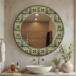 以下が含まれることがあります： 緑と金のフローラルデザインの模様の縁が付いた丸い装飾鏡。 鏡は白い洗面台の上にある明るい灰色のマーブルの壁に取り付けられており、スタイリッシュなバスルームのアクセントになっています。