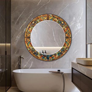 K&ouml;nnte beinhalten: Ein runder Buntglasspiegel mit farbenfrohem Blumenmuster. Der Rahmen ist ein Mosaik aus Orange, Gelb, Blau und Gr&uuml;n. Der Spiegel h&auml;ngt an einer grauen Marmorwand &uuml;ber einer wei&szlig;en Badewanne.