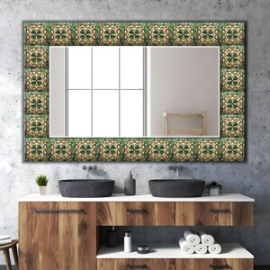 Può includere: Uno specchio da parete rettangolare con una cornice decorativa composta da piastrelle quadrate ripetute con un motivo a quadrifoglio verde e crema. La superficie dello specchio riflette una finestra con pannelli verticali e una sedia in legno.