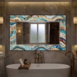 Può includere: Specchio rettangolare da bagno con bordo a mosaico in tonalità blu, beige e rosso. Lo specchio riflette una finestra e un interno scuro. Lo specchio è montato sopra una vasca da bagno bianca.