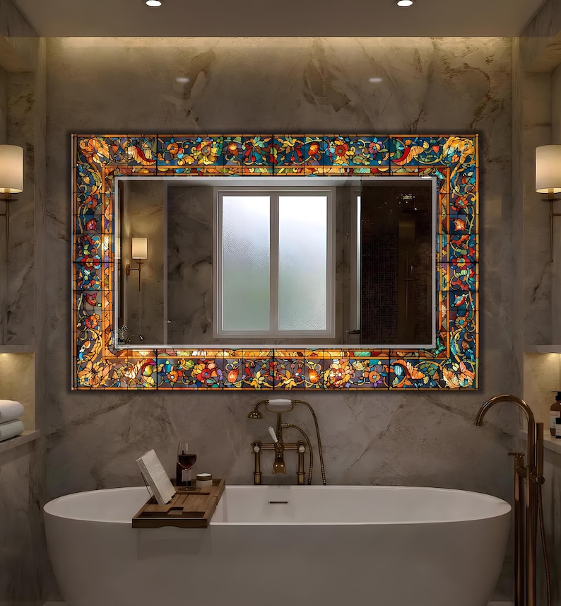 K&ouml;nnte beinhalten: Ein rechteckiger Spiegel mit einem Buntglasrand mit floralen und abstrakten Designs in Orange-, Blau-, Gelb- und Gr&uuml;nt&ouml;nen. Der Spiegel ist &uuml;ber einer wei&szlig;en Badewanne in einem Badezimmer angebracht.