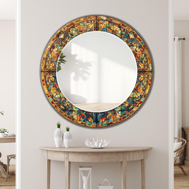 K&ouml;nnte beinhalten: Ein runder Spiegel mit einem Buntglas-Design-Rand. Der Rand zeigt ein Blumenmuster in Gelb-, Orange-, Blau- und Gr&uuml;nt&ouml;nen. Der Spiegel h&auml;ngt an einer wei&szlig;en Wand &uuml;ber einem Holztisch mit dekorativen Vasen.